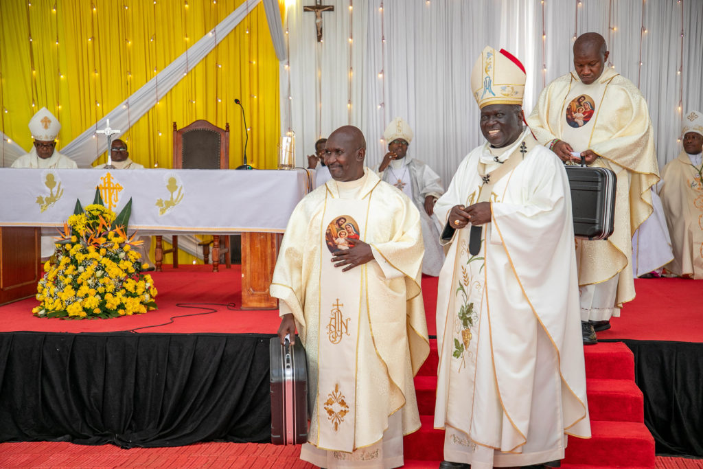 Fr. Steve Kungu being presented the Mass kit by the Archbishop.